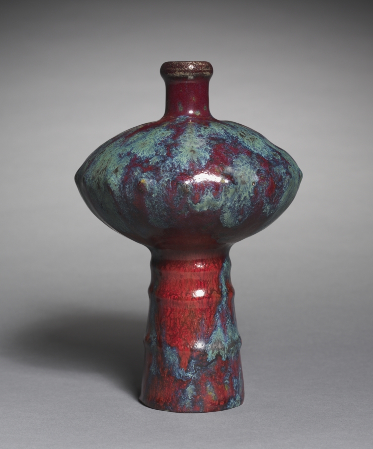 A vase with a wide blue shoulder, short red neck and long red foot.