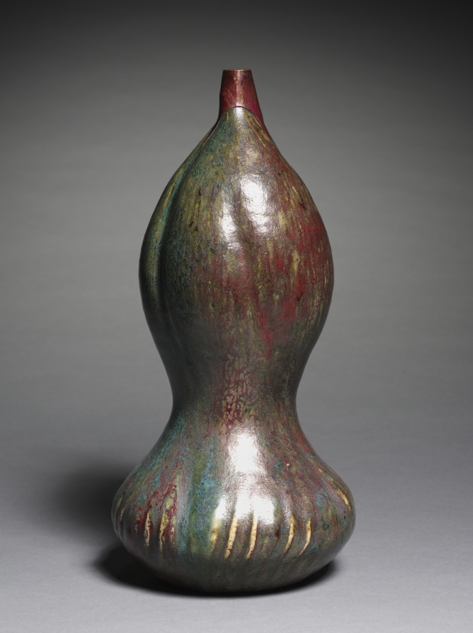 A tall gourd-shaped vase with a narrow neck and mottled green, red and cream glaze.