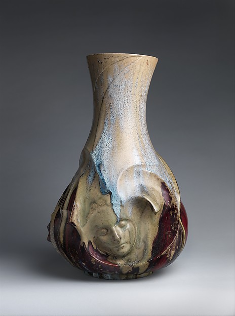 A tall pale vase curves outward above a sleeping face emerging from its darker base.